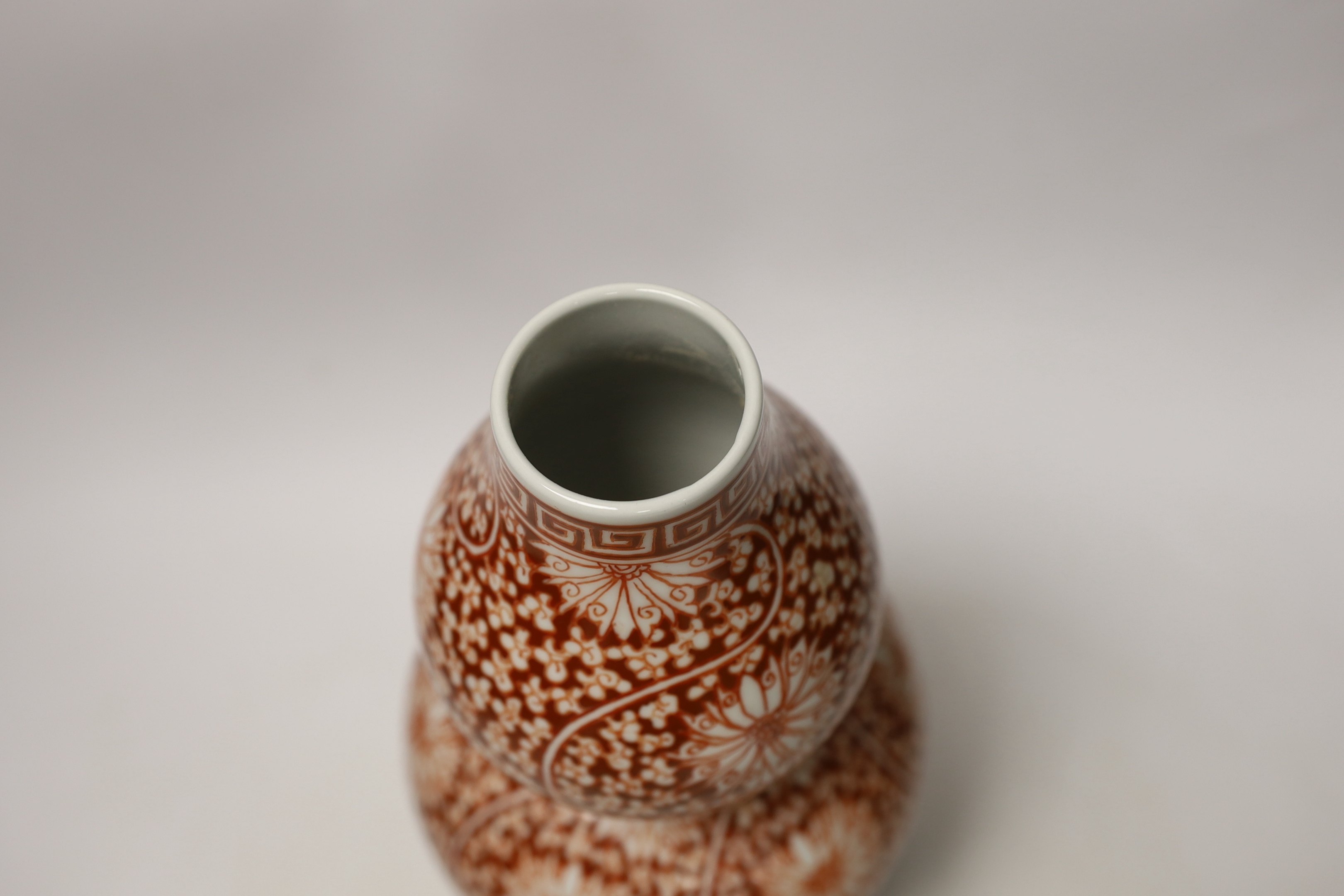 A Chinese iron-red double-gourd vase on hardwood stand, 29cm high